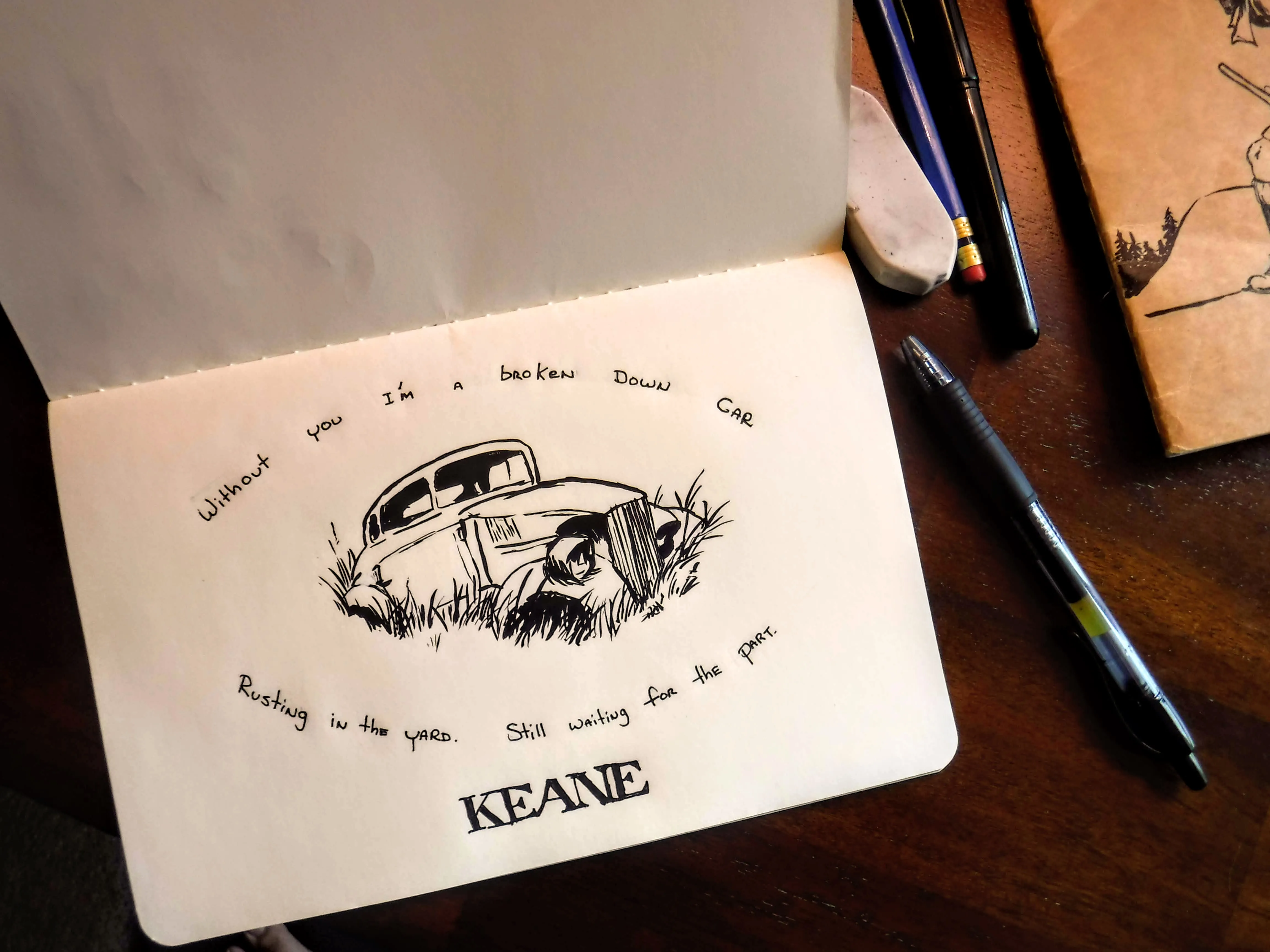 A sketchbook drawing of an old car rusting in tall grass, surrounded by handwritten song lyrics